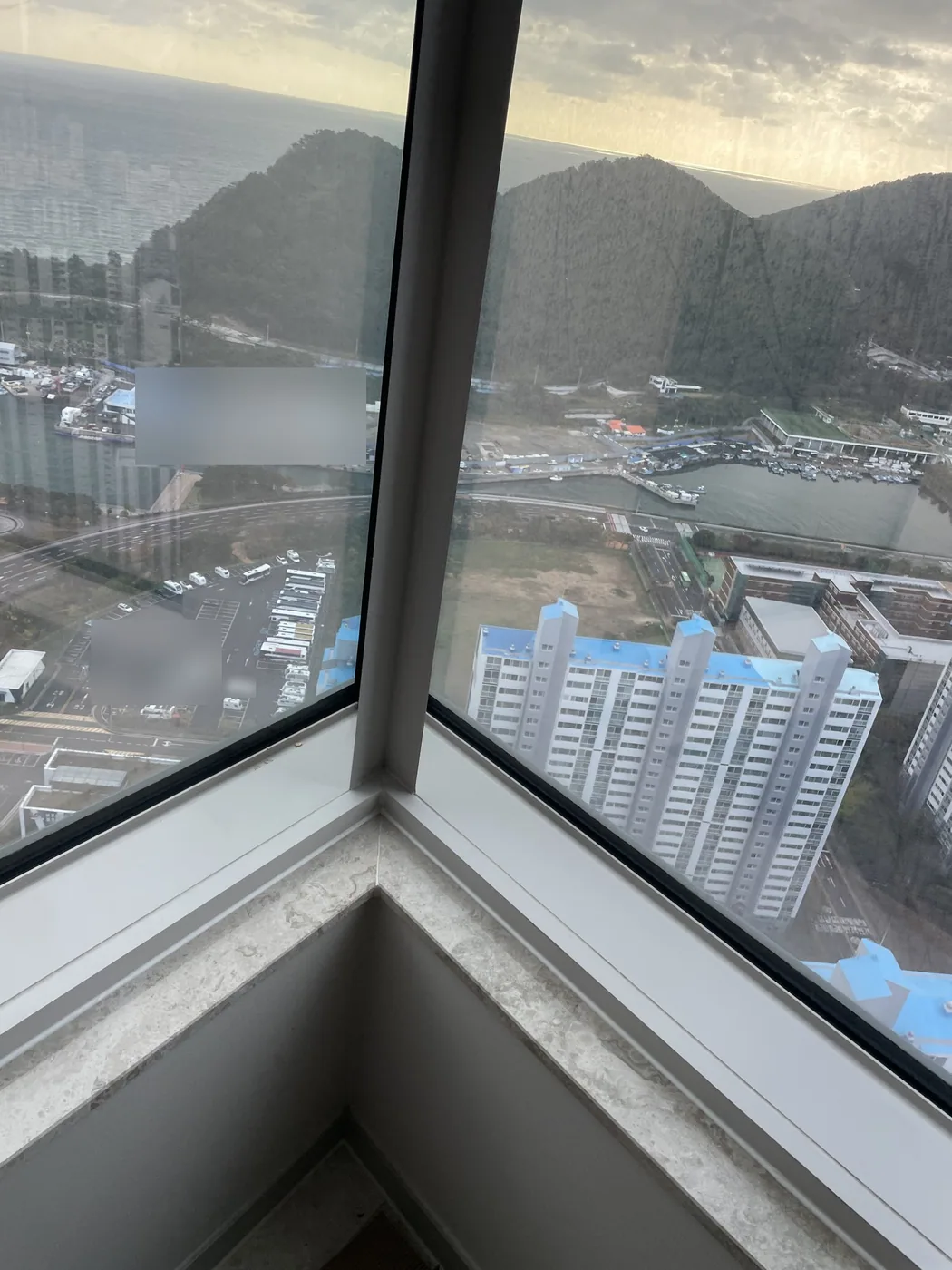 고층 세대 모서리에서 비스듬히 만나는 두 통창과 아래쪽 창턱