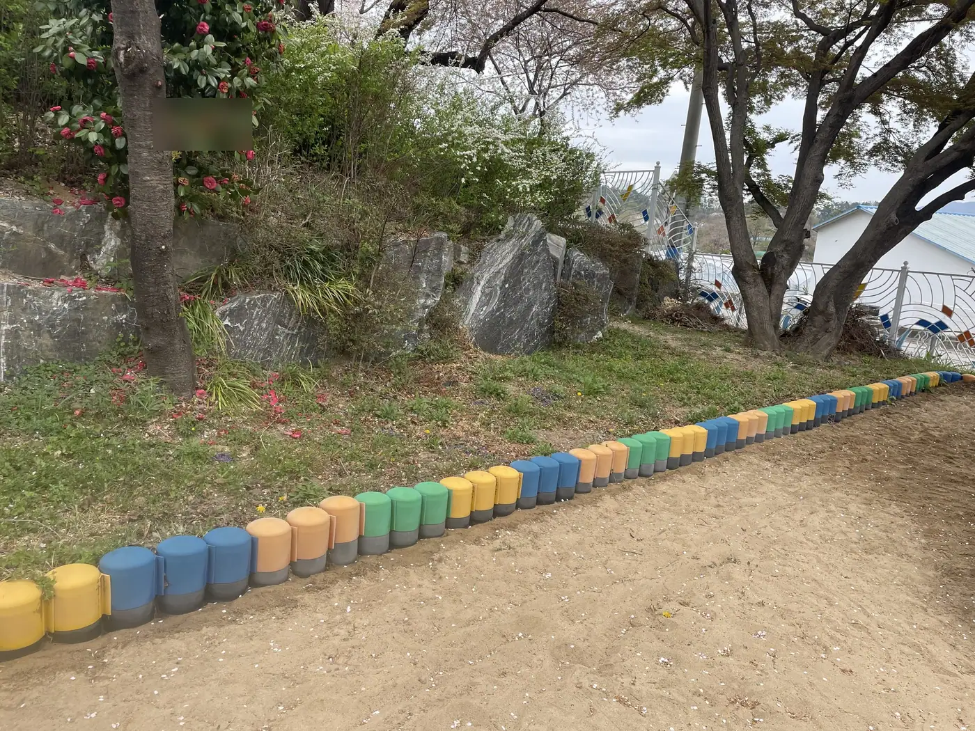 세척을 마친 둥근 경계석이 화단과 모래밭 사이를 따라 이어진 모습