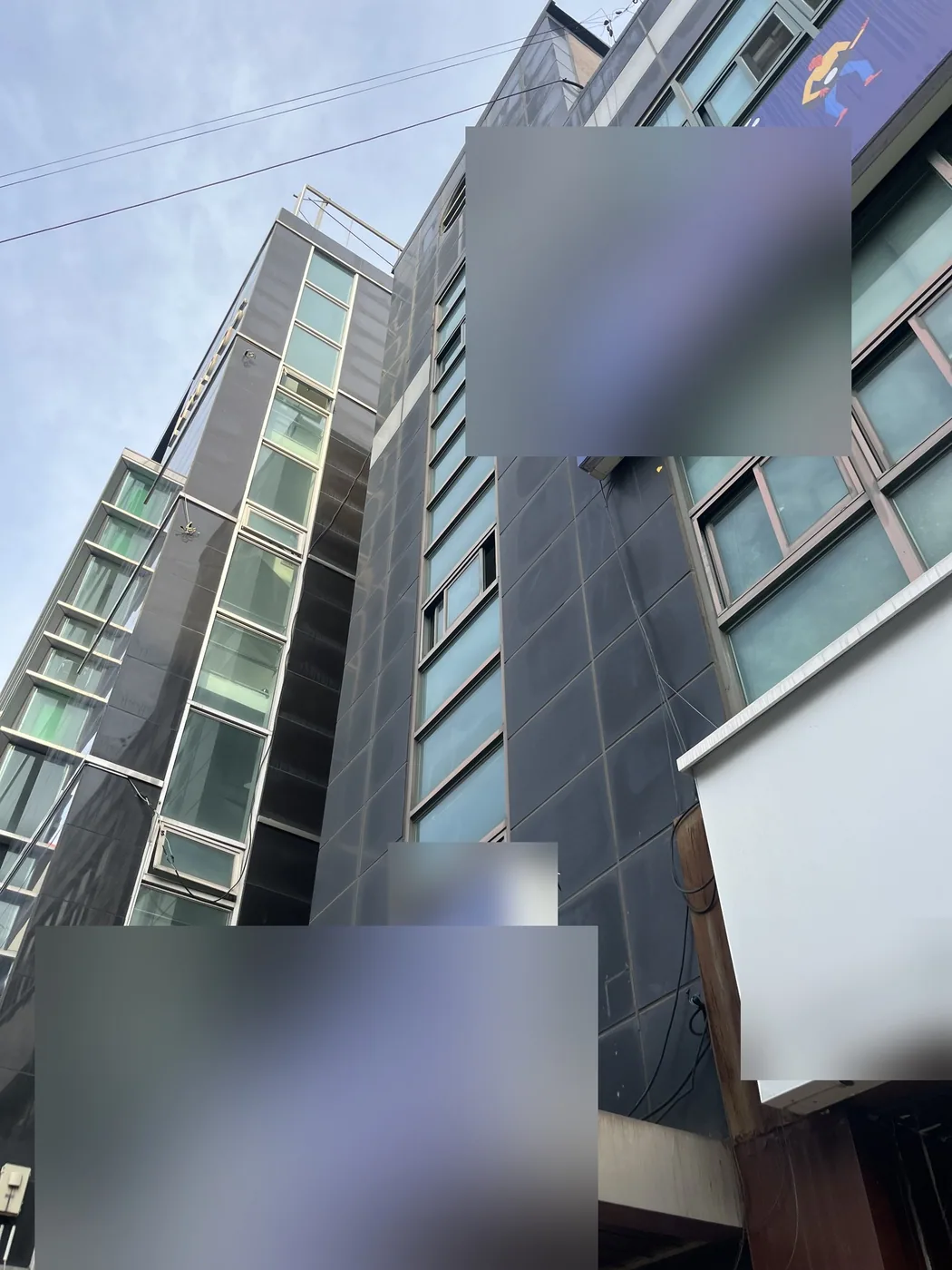 작업 전 아침에 올려다본 상가건물의 세로 창 라인과 짙은 색 외벽 패널