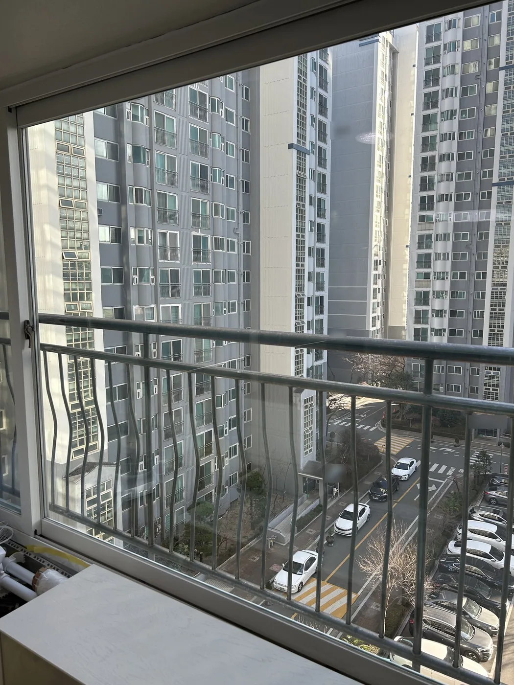 청소를 마친 난간 쪽 큰 창 너머로 보이는 아파트 단지와 주차장