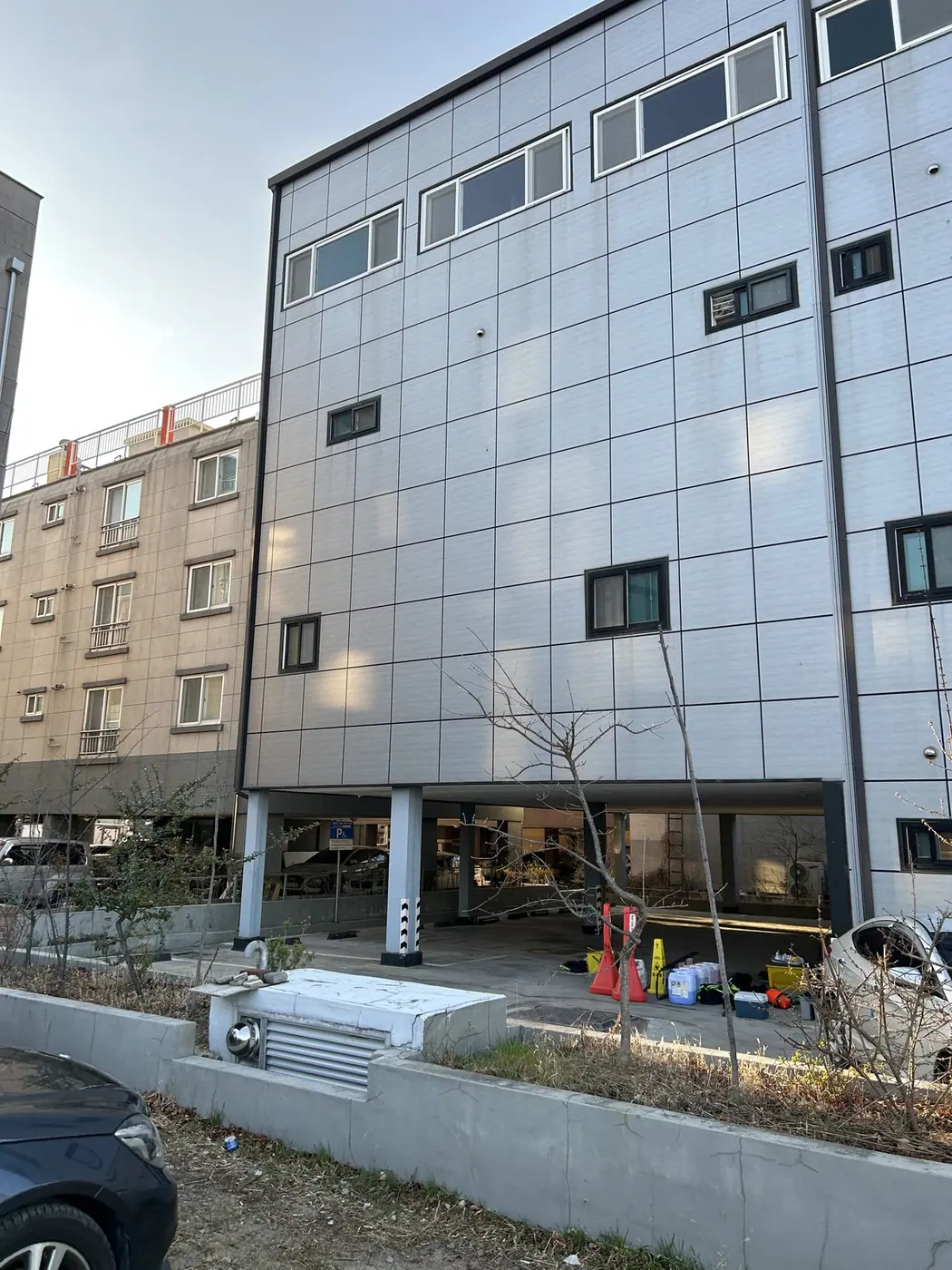 5층 상가건물의 회색 금속 판넬 외벽에 줄눈을 따라 먼지가 앉은 작업 전 모습