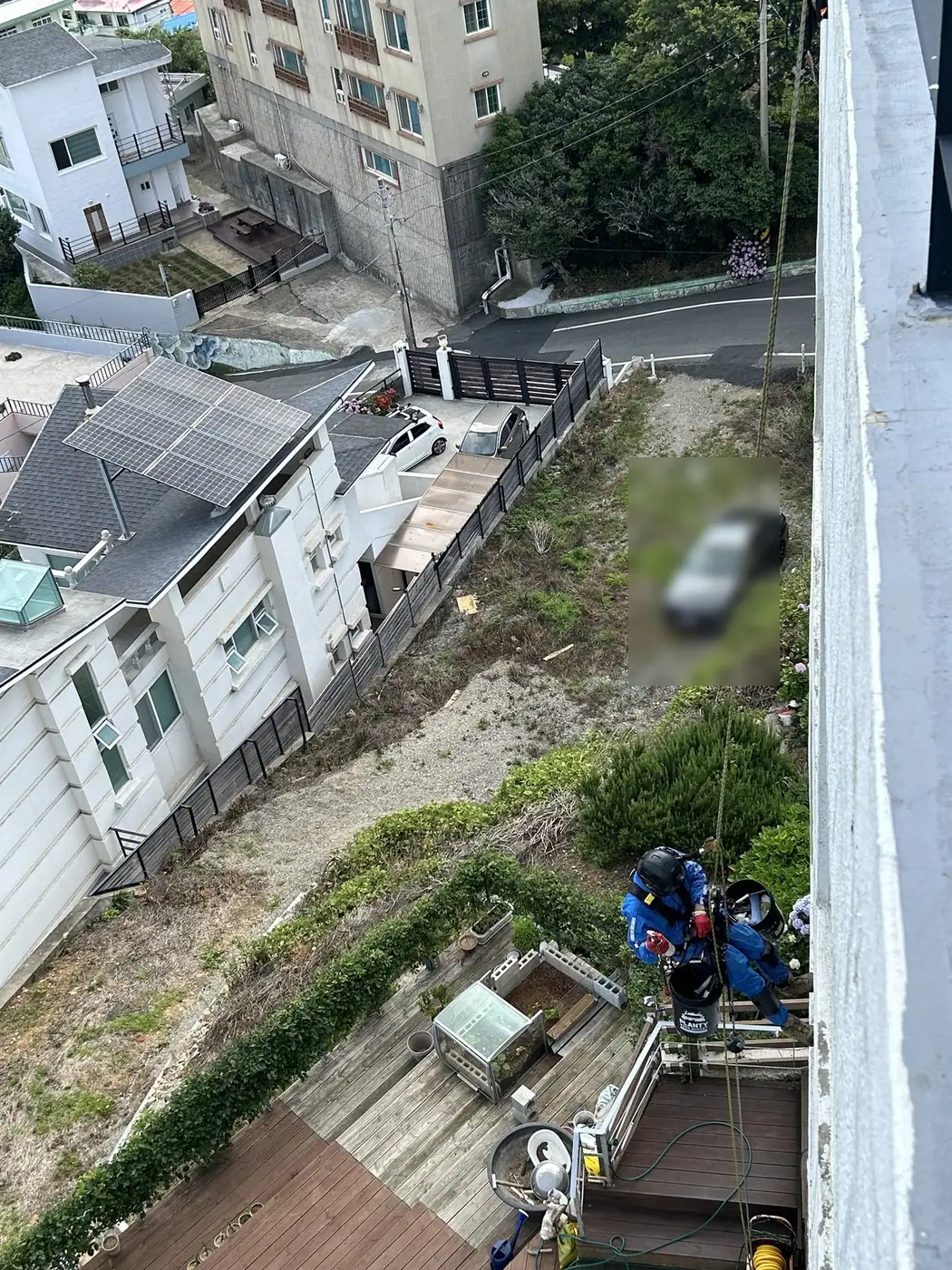 카페 건물 옆면 외벽을 로프를 타고 내려오며 세척하는 작업 중간 장면