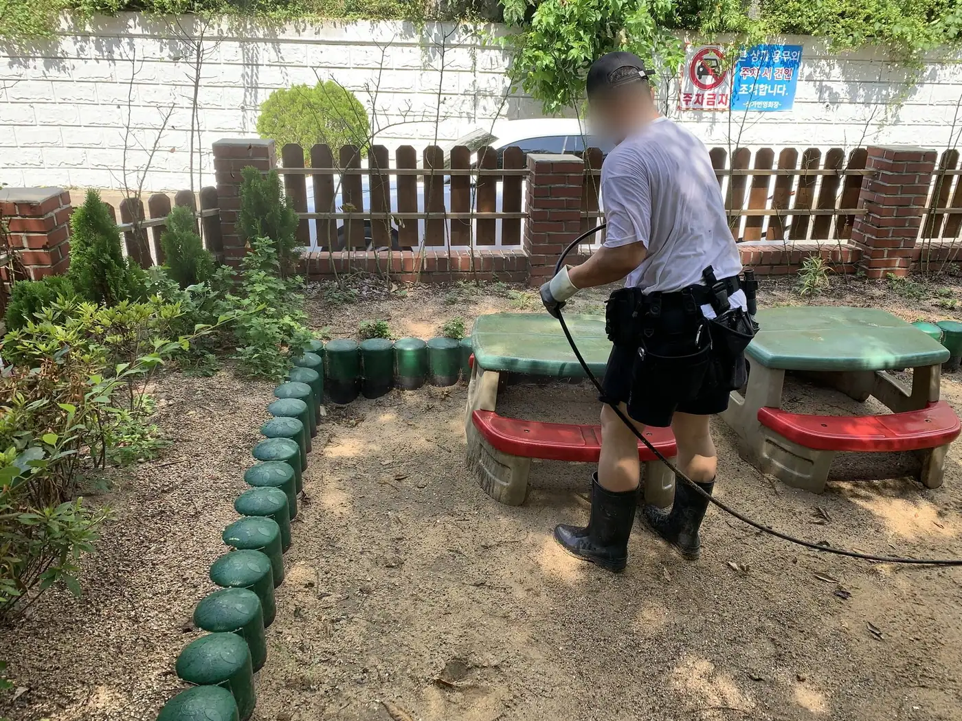 놀이터 주변 시설물과 바닥 경계를 세척하는 장면
