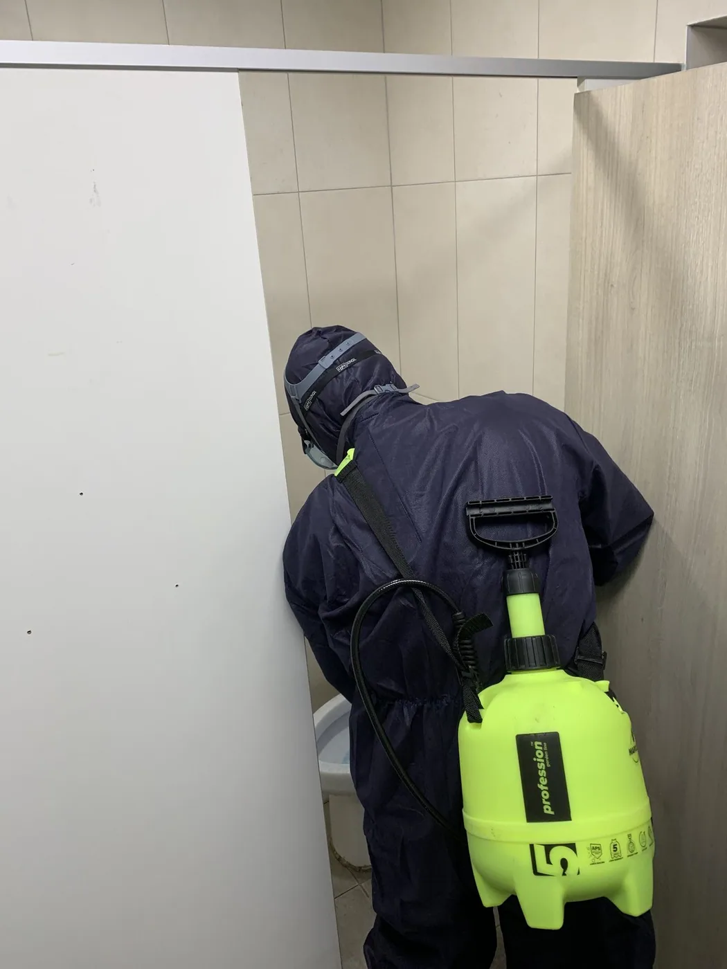 호흡 보호구와 작업복을 갖추고 실내에서 작업하는 장면