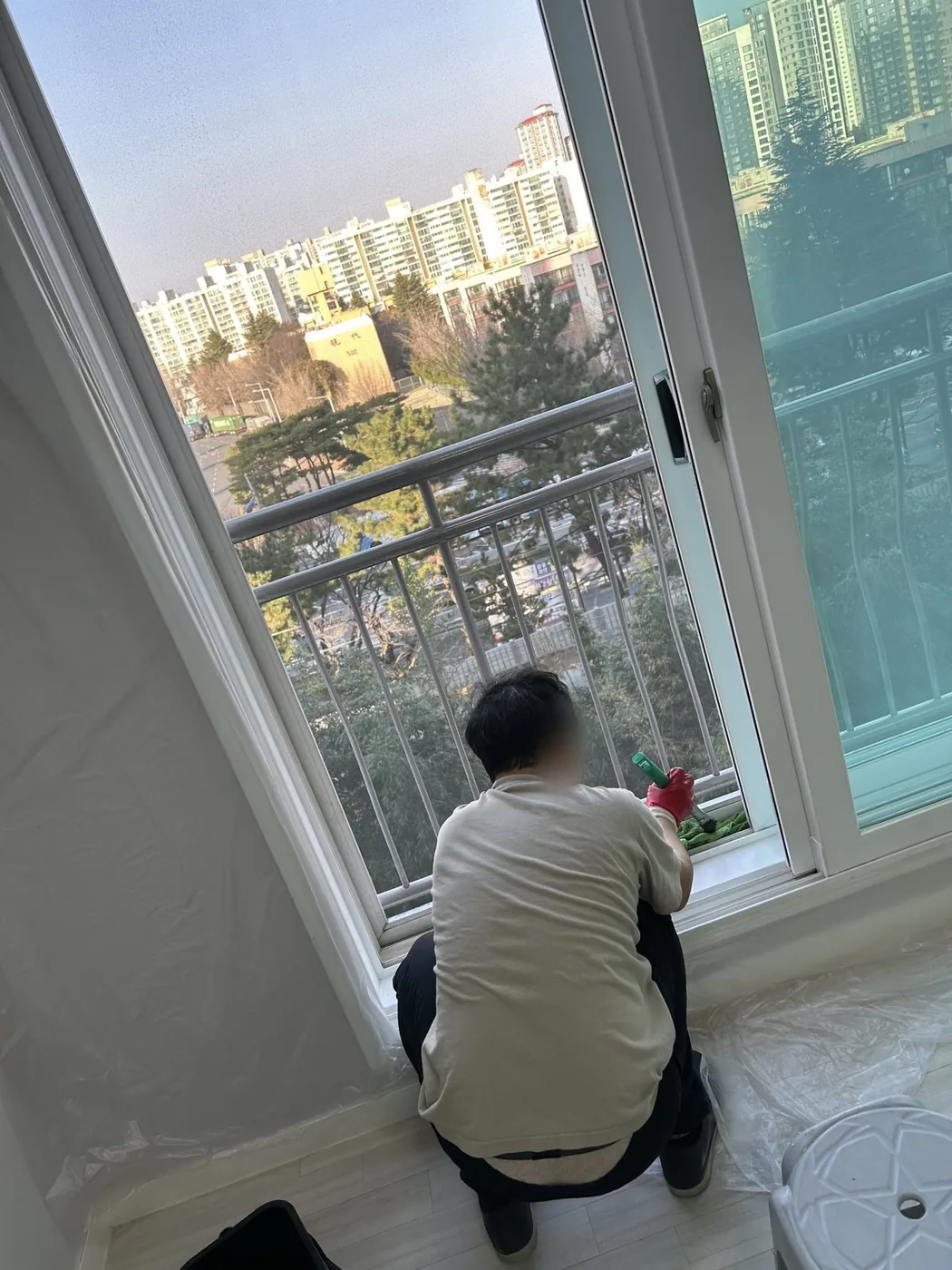 창틀 아래쪽에 앉아 배수 구멍 주변을 확인하며 작업하는 장면