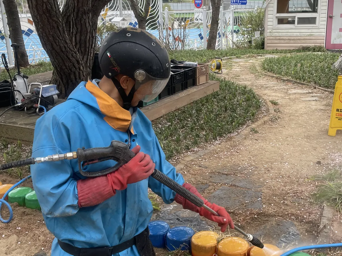 놀이터 경계석을 고압수로 씻어 내는 작업자